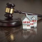 Gavel and Small Model House on Wooden Table.