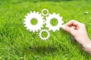 Hand holding gears against a backdrop of green grass