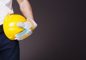 Image of a worker holding a helmet against grey background