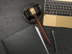Wooden judges gavel and laptop computer on black leather desk