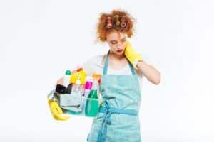 Exhausted woman holding cleaning supplies and having neck pain
