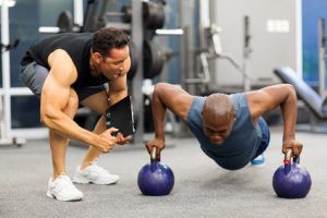 personal trainer motivates client doing push-ups